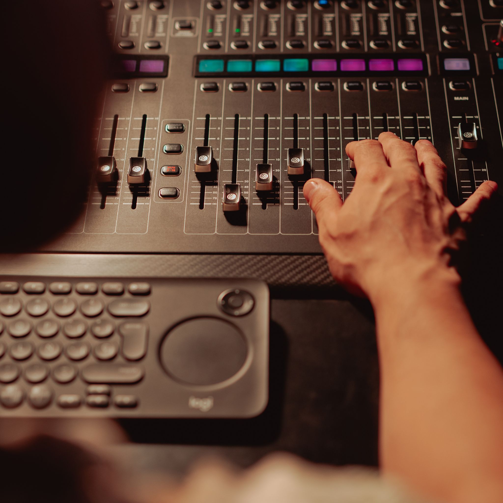 main d un DJ sur une console de mixage avec faders et pads colores allumes en soiree