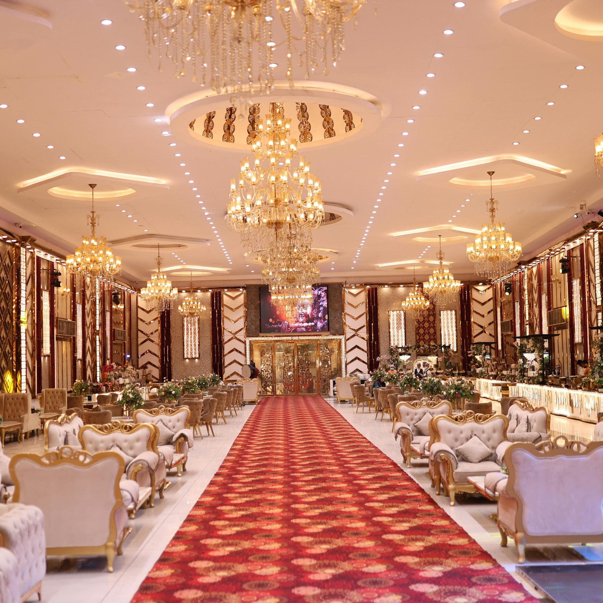 salle de reception avec tapis rouge lustres en cristal et fauteuils dores prete pour un mariage