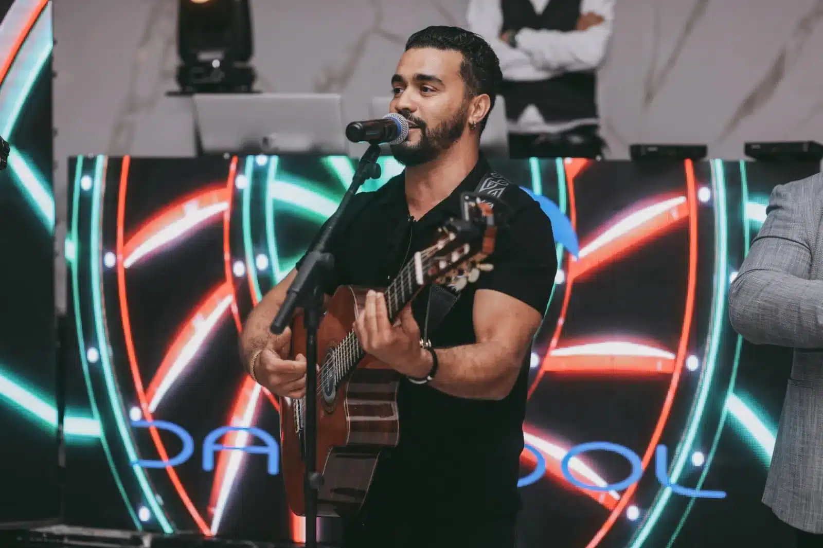 Chanteur guitariste au micro devant écran néon LED lors d'une soirée d'anniversaire à Paris