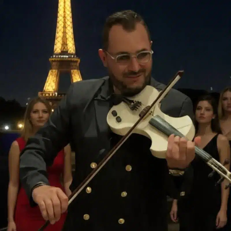 Kinanviolon, violoniste live de l'équipe DJ Dadicool, jouant du violon électrique blanc devant la Tour Eiffel illuminée à Paris