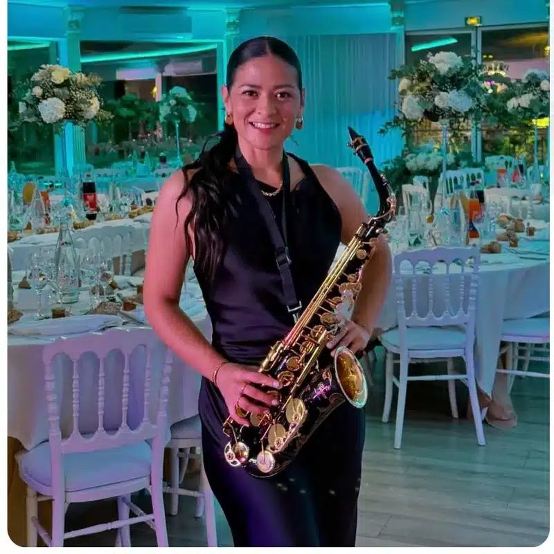Bellasax, saxophoniste de l'équipe DJ Dadicool, en robe noire avec saxophone alto dans une salle de mariage prestige éclairée turquoise