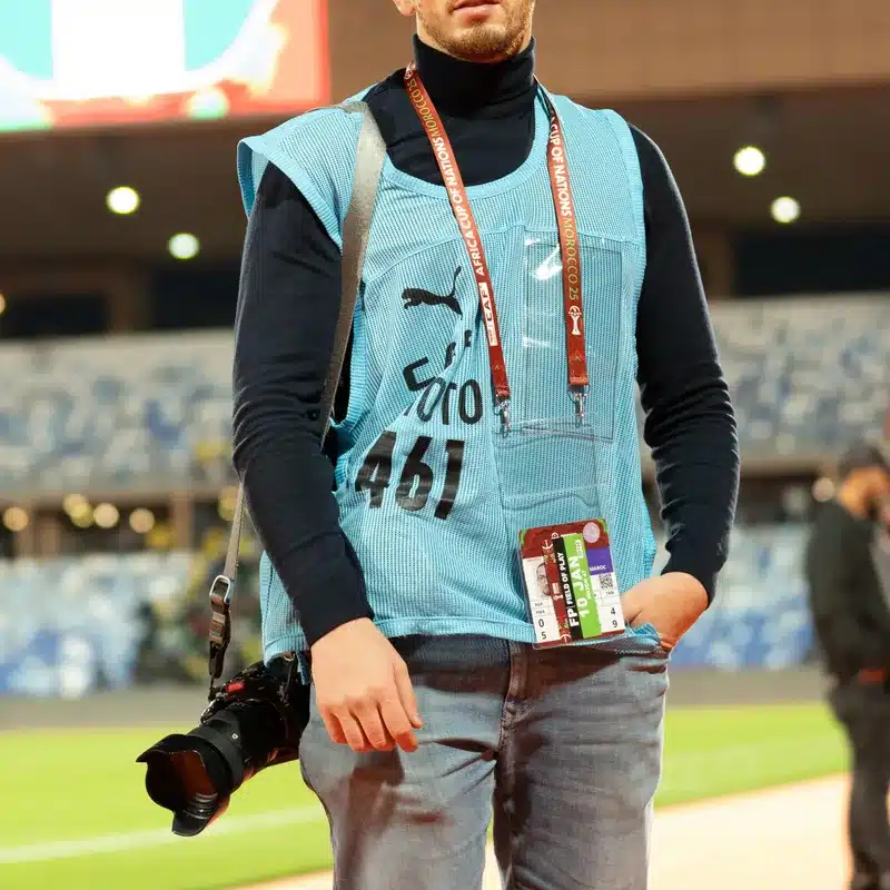 Oussama, vidéaste et photographe de l'équipe DJ Dadicool, portrait extérieur avec caméra professionnelle