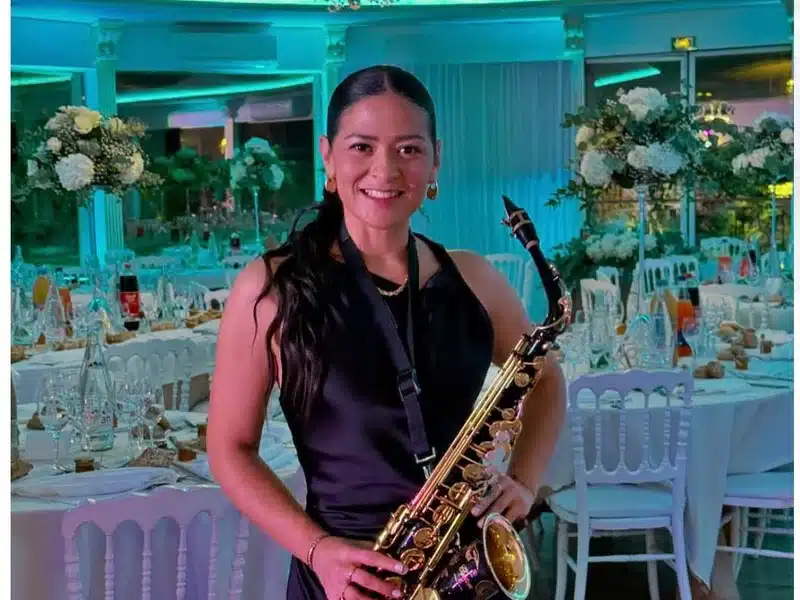 Bellasax, saxophoniste de l'équipe DJ Dadicool, saxophone alto en main dans une salle de réception